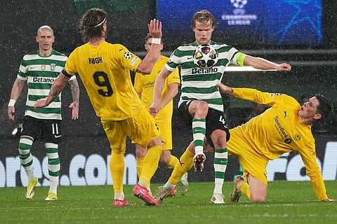 Sporting's Morten Hjulmand, center, is challenged by Glimt's Kasper Hogh, left, during a Champions League round of 16 second leg soccer match between Sporting CP and Bodo Glimt in Lisbon, Portugal.