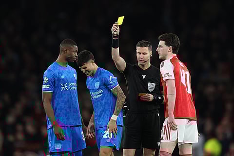 Referee Danny Makkelie shows a yellow card to Leverkusen's Exequiel Palacios, second left, during the second leg of the Champions League round of 16 soccer match between Arsenal and Bayer Leverkusen, in London.