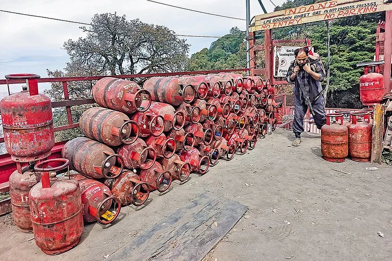 A worker carries an LPG cylinder for distribution in Shimla, Himachal Pradesh