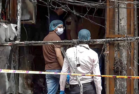 Forensic team and Delhi Police personnel inspect a building to collect evidence after a fire in Palam, in New Delhi. According to officials, at least nine people, including three children, were killed. 