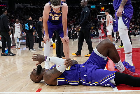 Los Angeles Lakers' LeBron James reaches for his elbow after hitting court while being fouled by Houston Rockets' Jabari Smith Jr. during the second half of an NBA basketball game in Houston.