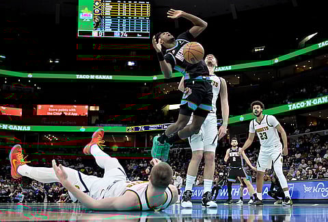 Memphis Grizzlies forward Olivier-Maxence Prosper, left center, shoots against Denver Nuggets center Nikola Jokic, center right, in the second half of an NBA basketball game in Memphis, Tennessee.