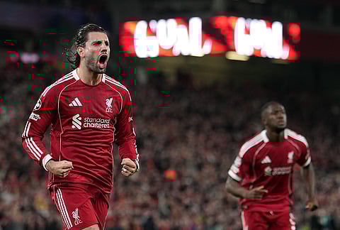 Liverpool's Dominik Szoboszlai, left, celebrates after scoring the opening goal during the second leg of the Champions League round of 16 soccer match between Liverpool and Galatasaray, in Liverpool, England.