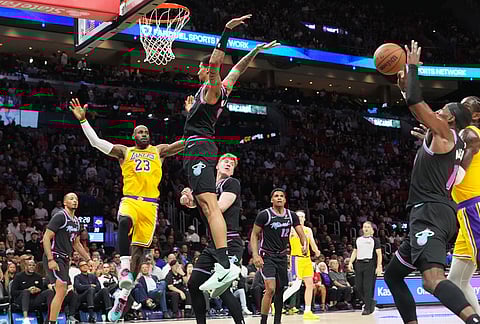 Los Angeles Lakers forward LeBron James (23) attempts to pass as Miami Heat center Bam Adebayo, right, goes for the ball during the first half of an NBA basketball game, in Miami. 