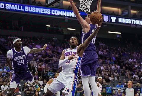 Philadelphia 76ers forward Justin Edwards, front, goes for a layup against Sacramento Kings center Maxime Raynaud, rear right, during the first half of an NBA basketball game in Sacramento, California. 