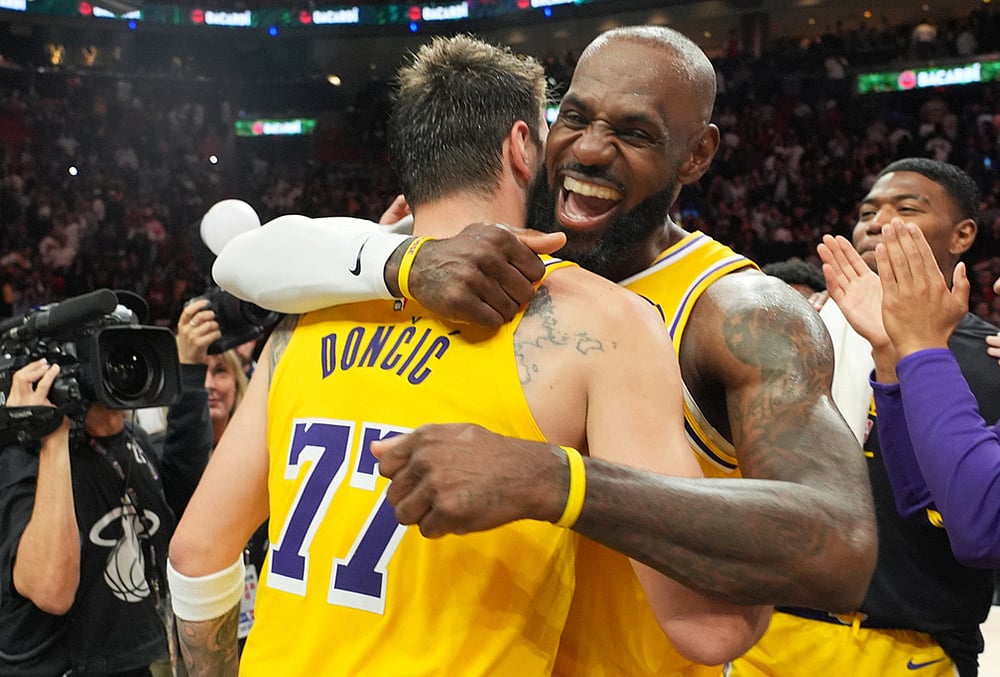 Los Angeles Lakers guard Luka Doncic (77) and forward LeBron James, right, embrace after defeating the Miami Heat in an NBA basketball game, in Miami. - | Photo: AP/Lynne Sladky