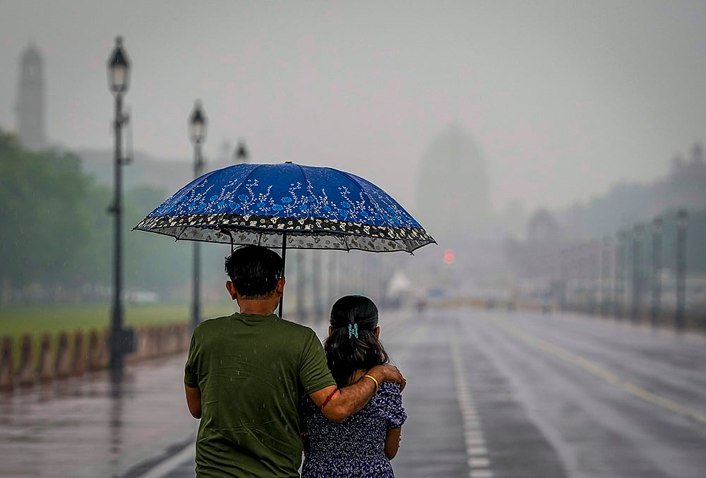 Visitors make their way through the Kartavya Path amid rainfall, in New Delhi. The weather office has issued a yellow alert for the city.  - | Photo: PTI/Atul Yadav