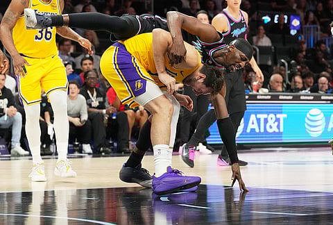 Miami Heat center Bam Adebayo, top, collides with Los Angeles Lakers guard Luka Doncic during the second half of an NBA basketball game, in Miami.