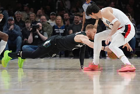 Minnesota Timberwolves guard Donte DiVincenzo, left, dives for the ball next to Portland Trail Blazers forward Deni Avdija, right, during the first half of an NBA basketball game in Minneapolis. 