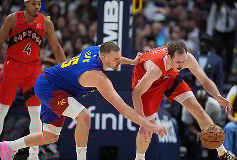Denver Nuggets center Nikola Jokic, left, pursues a loose ball with Toronto Raptors center Jakob Poeltl in the second half of an NBA basketball game in Denver.