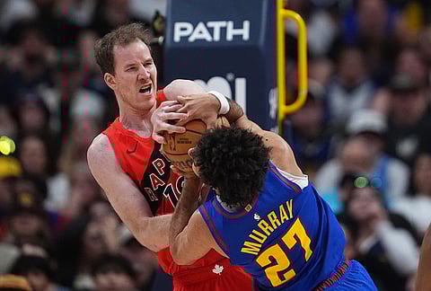 Toronto Raptors center Jakob Poeltl, back, ties up Denver Nuggets guard Jamal Murray as he drives to the rim in the second half of an NBA basketball game in Denver. 