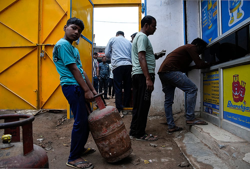 people line up and wait at a distribution agency for LPG cylinders