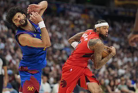 Denver Nuggets guard Jamal Murray, left, reacts after he was hit as Toronto Raptors forward Brandon Ingram drives the lane for a shot in the second half of an NBA basketball game in Denver. 