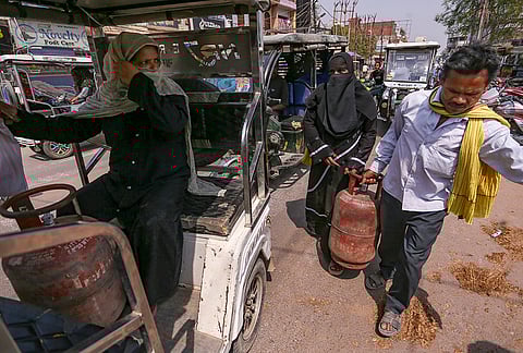 People carry LPG cooking gas cylinders, amid a shortage linked to the ongoing West Asia conflict affecting the global energy supply chain, in Prayagraj.