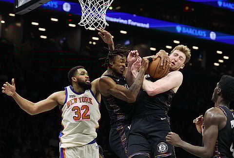 Brooklyn Nets center Nic Claxton, left, and teammate Danny Wolf, right, both go for the rebound during the second half of an NBA basketball game against the New York Knicks, in New York.