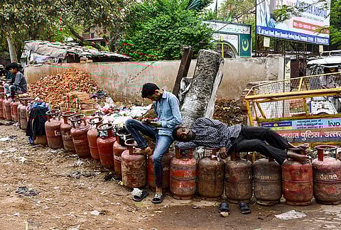 People wait with empty LPG cooking gas cylinders to avail refilled ones, in Prayagraj.