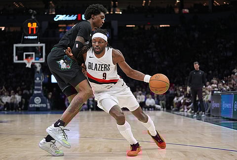 Portland Trail Blazers forward Jerami Grant (9) works toward the basket as Minnesota Timberwolves forward Jaden McDaniels (3) defends during the second half of an NBA basketball game in Minneapolis. 