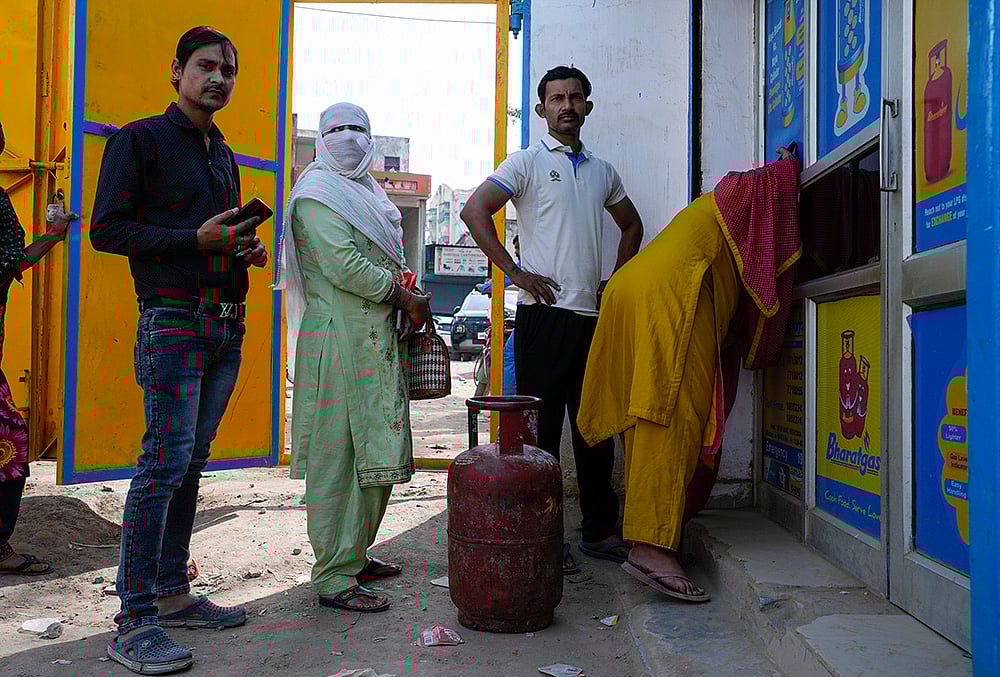 Residents of Badhkal, line up and wait at a distribution agency for LPG cylinders