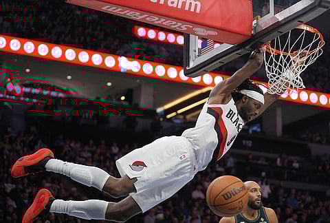 Portland Trail Blazers forward Jerami Grant, top, hangs from the rim after a dunk during the second half of an NBA basketball game against the Minnesota Timberwolves, in Minneapolis. 