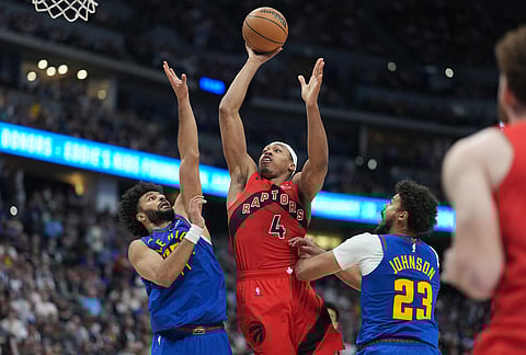 Toronto Raptors forward Scottie Barnes, center, drives to the rim between Denver Nuggets guard Jamal Murray, left, and forward Cameron Johnson in the second half of an NBA basketball game in Denver.