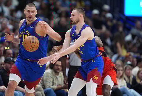 Denver Nuggets guard Christian Braun, front right, passes the ball to center Nikola Jokic, left, as Toronto Raptors guard Immanuel Quickley defends in the second half of an NBA basketball game in Denver. 