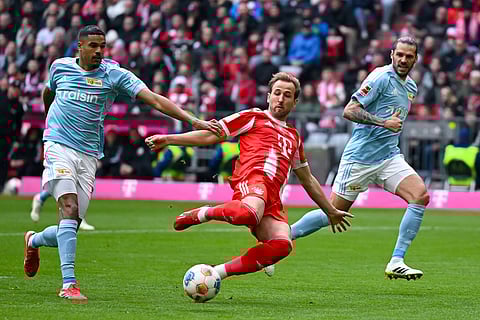 Munich's Harry Kane, center, and Berlin's Livan Burcu, left, challenge for the ball during the German Bundesliga soccer match between FC Bayern Munich and 1. FC Union Berlin in Munich, Germany.