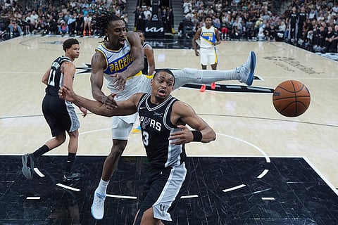 Indiana Pacers guard Aaron Nesmith, center, and San Antonio Spurs forward Keldon Johnson (3) scramble for a rebound during the second half of an NBA basketball game in San Antonio.