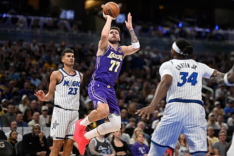 Los Angeles Lakers guard Luka Doncic (77) goes up to shoot between Orlando Magic forward Tristan da Silva (23) and center Wendell Carter Jr. (34) during the first half of an NBA basketball game in Orlando, Fla.