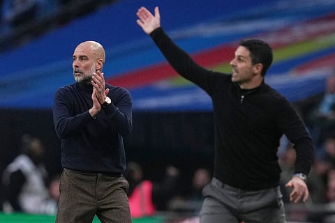 Manchester City's head coach Pep Guardiola, left encourages his players as Arsenal's manager Mikel Arteta gestures to his during the English League Cup final soccer match between Arsenal and Manchester City in London, Sunday, March 22, 2026.