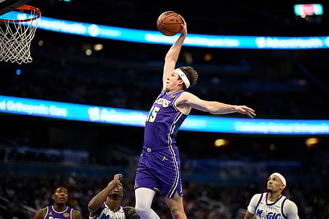 Los Angeles Lakers guard Austin Reaves (15) goes up to dunk between Orlando Magic forward Jamal Cain, second from left, and guard Jalen Suggs, right, during the first half of an NBA basketball game in Orlando, Fla.