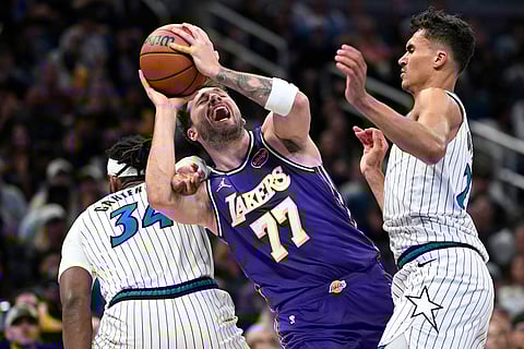Los Angeles Lakers guard Luka Doncic (77) is fouled by Orlando Magic center Wendell Carter Jr. (34) as Magic forward Tristan da Silva, right, helps defend during the first half of an NBA basketball game in Orlando, Fla.