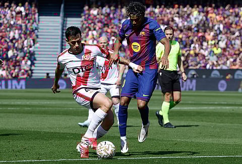 Rayo's Pedro Diaz, left, and Barcelona's Lamine Yamal fight for the ball during a La Liga soccer match between Barcelona and Rayo Vallecano in Barcelona, Spain.