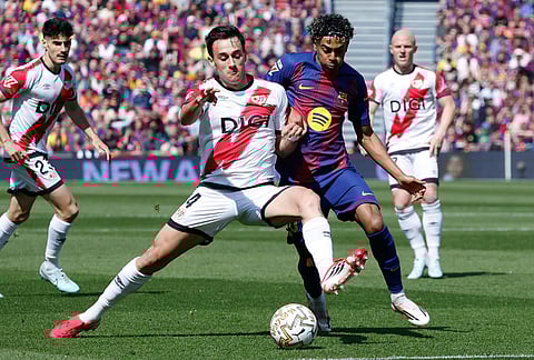 Rayo's Pedro Diaz, left, and Barcelona's Lamine Yamal fight for the ball during a La Liga soccer match between Barcelona and Rayo Vallecano in Barcelona, Spain.