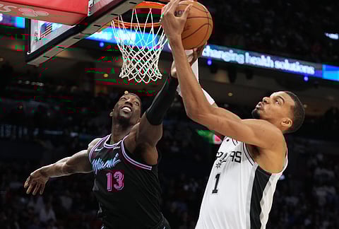 Miami Heat center Bam Adebayo (13) goes for a rebound against San Antonio Spurs forward Victor Wembanyama (1) during the second half of an NBA basketball game, in Miami.