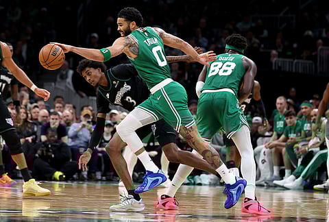 Boston Celtics forward Jayson Tatum (0) defends the ball from Minnesota Timberwolves forward Jaden McDaniels (3) during the second half of an NBA basketball game, in Boston. 
