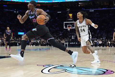 Miami Heat center Bam Adebayo (13) drives to the basket past San Antonio Spurs forward Emanuel Miller (14) during the second half of an NBA basketball game, in Miami. 