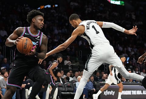 Miami Heat's Davion Mitchell, left, grabs a rebound over San Antonio Spurs forward Victor Wembanyama (1) during the first half of an NBA basketball game, in Miami. 