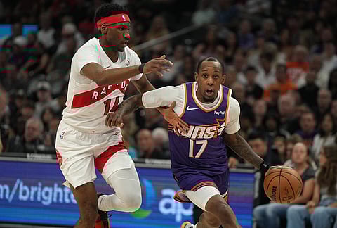 Phoenix Suns guard Jamaree Bouyea (17) drives past Toronto Raptors guard Ja'kobe Walter during the first half of an NBA basketball game, in Phoenix. 