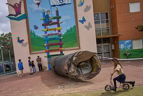 Children play beside a fragment of an Iranian ballistic missile that landed in a schoolyard in the Israeli settlement of Peduel in the West Bank. 
