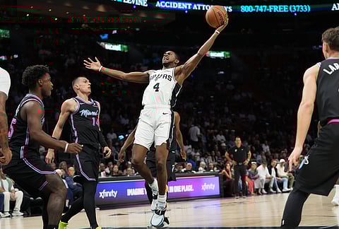 San Antonio Spurs guard De'aaron Fox (4) goes to the basket against Miami Heat guard Tyler Herro (14) during the first half of an NBA basketball game, in Miami.