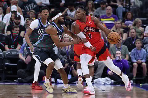 Toronto Raptors forward RJ Barrett (9) moves the ball as Utah Jazz guard Elijah Harkless, left, defends during the first half of an NBA basketball game in Salt Lake City.