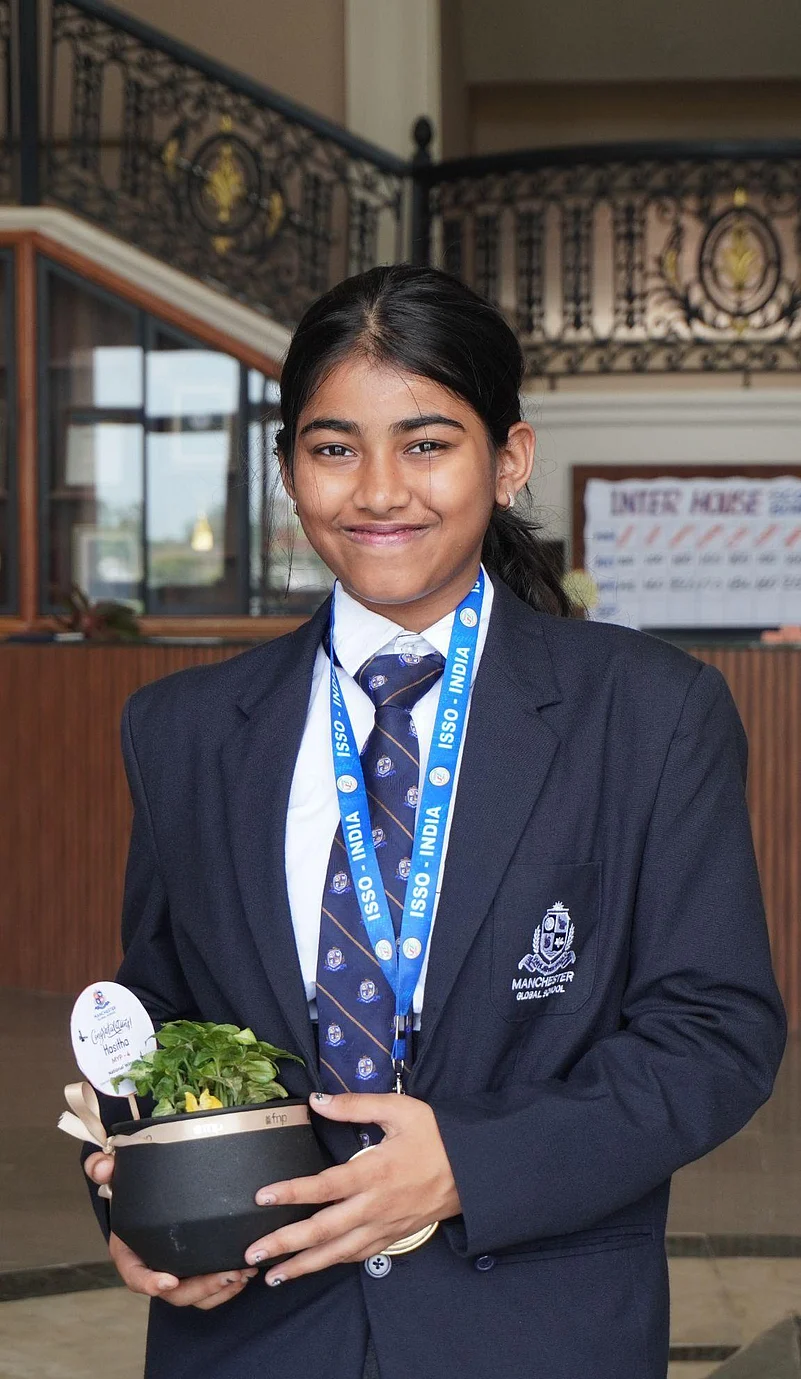 Student in school uniform holding a small plant