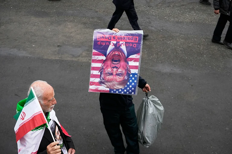 A man holds a picture of U.S. President Donald Trump upside down after Friday prayers at the Imam Khomeini Grand Mosque in Tehran, Iran, Friday, March 20, 2026 - AP Photo/Vahid Salemi