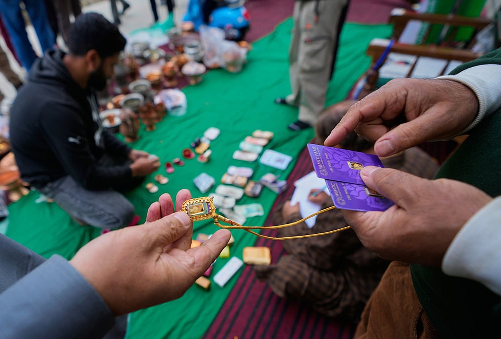 A volunteer examines the authenticity of donated gold jewelry during a relief drive for Iran in Budgam, Kashmir.