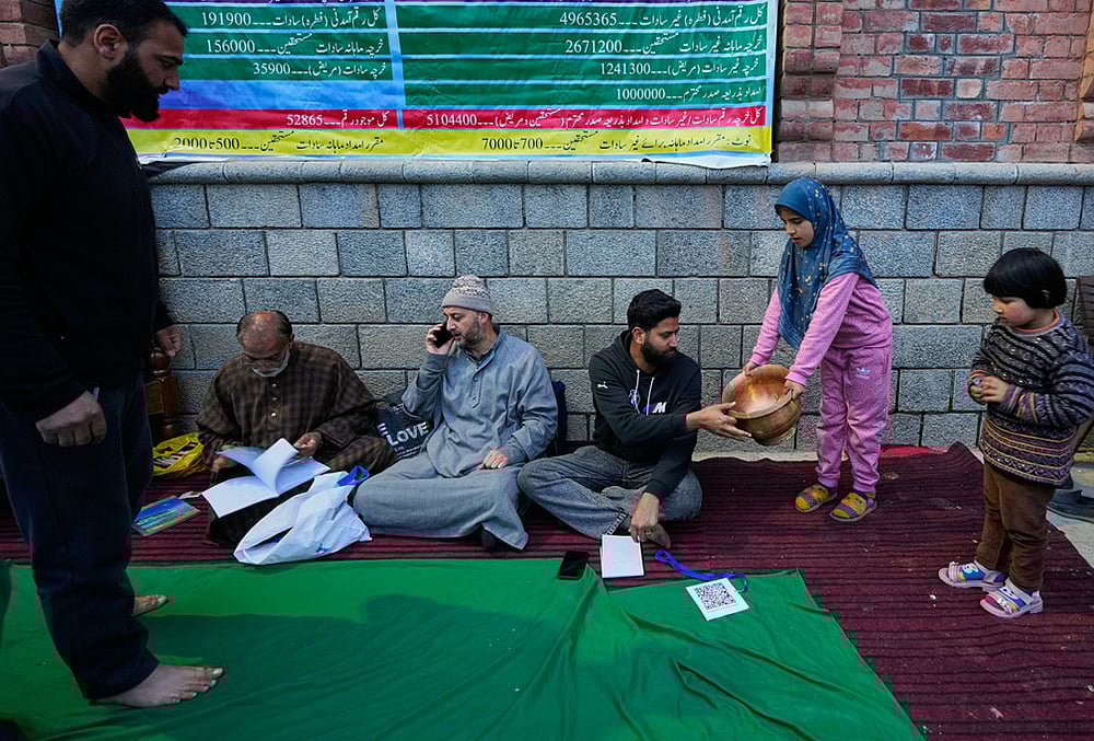 A girl donates a copper vessel during a relief drive for Iran in Budgam, Kashmir.