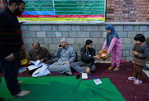 A girl donates a copper vessel during a relief drive for Iran in Budgam, Kashmir.