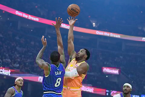 Cleveland Cavaliers guard Donovan Mitchell, right, shoots over Orlando Magic forward Jamal Cain (8) in the first half of an NBA basketball game in Cleveland.