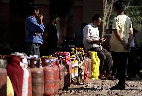 People wait in a queue with empty LPG cooking gas cylinders to avail refilled ones amid the ongoing supply crisis, in Prayagraj.