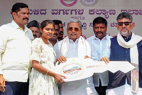 Karnataka Chief Minister Siddaramaiah, centre, presents a demo key to a beneficiary under the ‘Swavalambi Sarathi’ scheme during a vehicle distribution programme organised by the Backward Classes Welfare Department and various community development corporations, near Vidhana Soudha, in Bengaluru. State Deputy CM DK Shivakumar, right, and state Backward Classes Welfare Minister Shivaraj Tangadagi, left, are also present. 