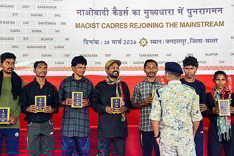 Senior Maoist commander Papa Rao, centre, a member of the Dandakaranaya Special Zonal Committee (DKSZC) and in-charge of south Sub Zonal Bureau of Maoists, and his team members hold copies of the Constitution of India after their surrender, in Bastar district, Chhattisgarh.